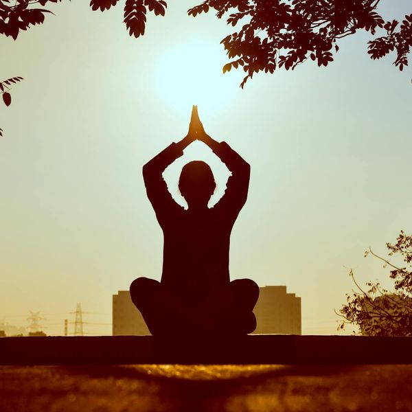 Person meditating peacefully outdoors at sunrise, symbolizing balance.